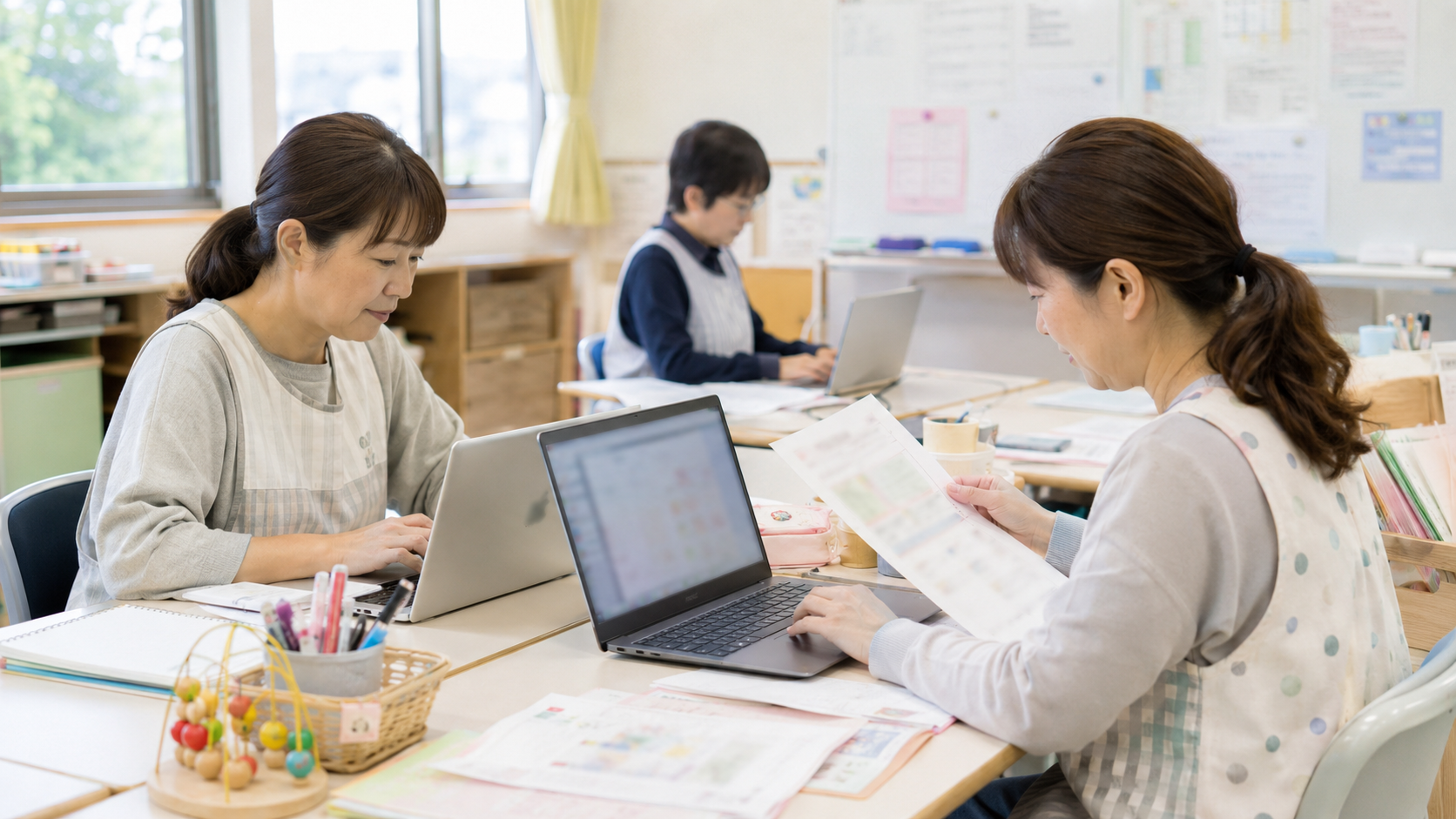 幼稚園や保育園で職員が園だよりや保護者向け文書を作成している様子